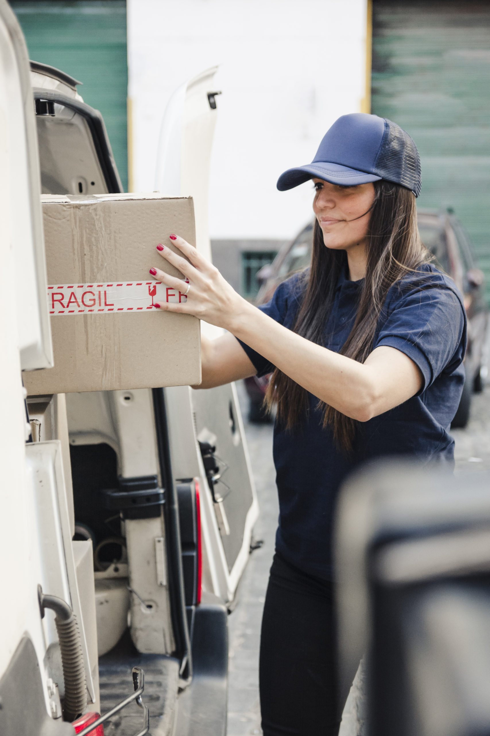 young-female-courier-unloaded-cardboard-box-from-vehicle